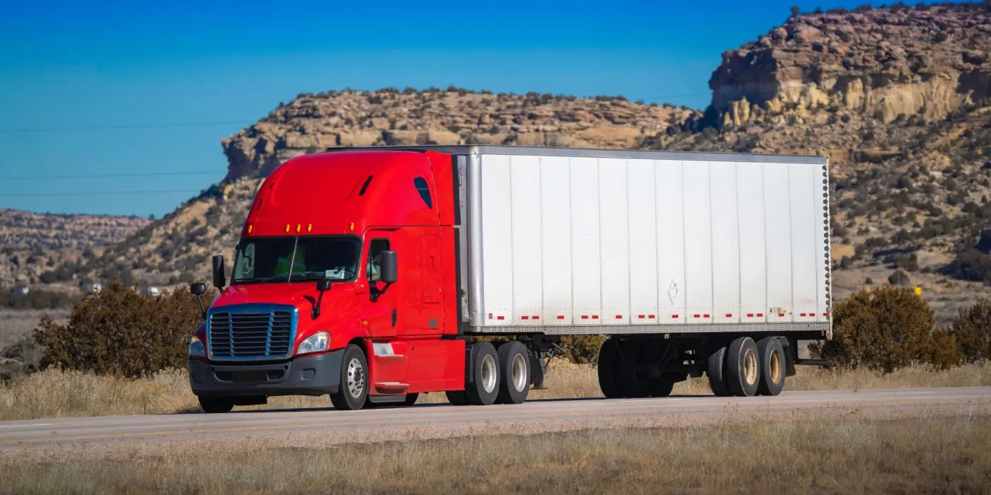 top-benefits-of-implementing-fleet-management-systems Red delivery semi-truck transporting freight on an open road, highlighting efficient commercial fleet tracking