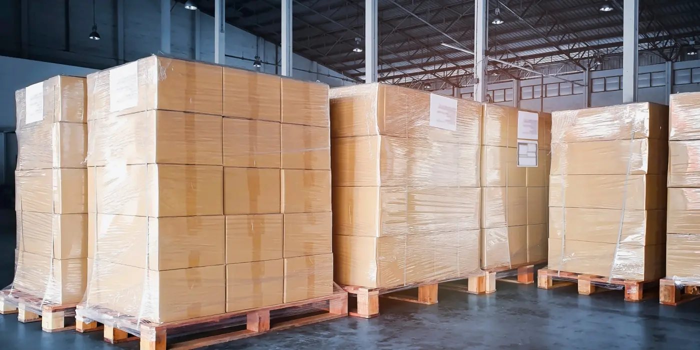 how-3pls-support-seasonal-peaks-and-holiday-surges Pallets of boxed inventory wrapped in plastic inside a warehouse, illustrating 3PL capacity for seasonal demand surges.